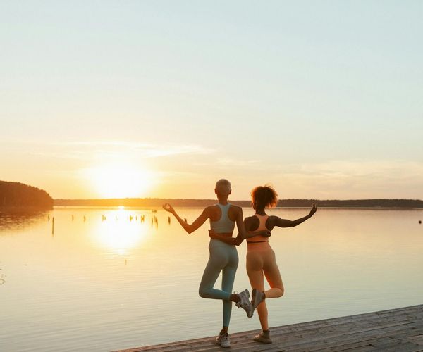 Person stretching gently outdoors during sunrise.
