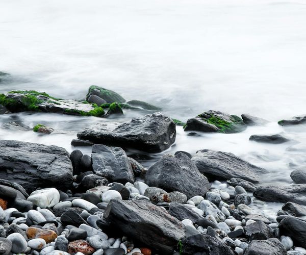 Smooth stones stacked by a calm body of water.